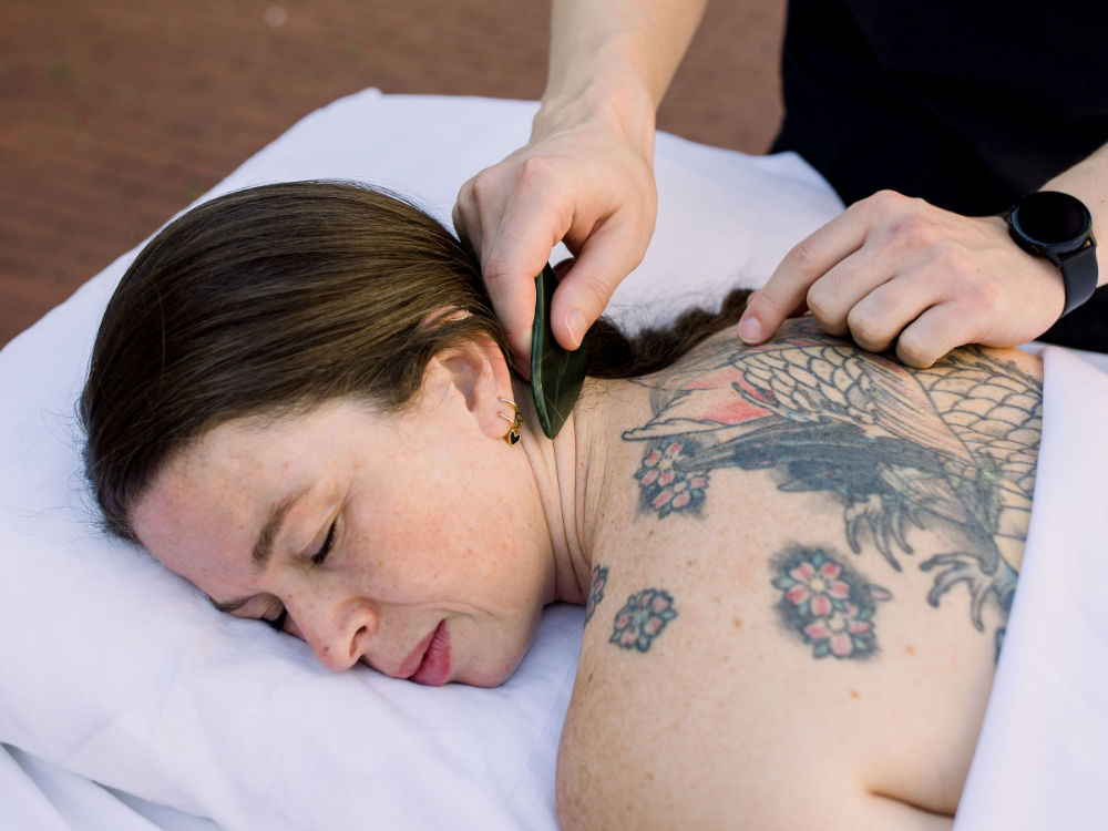 Women laying down receiving a Gua Sha treatment