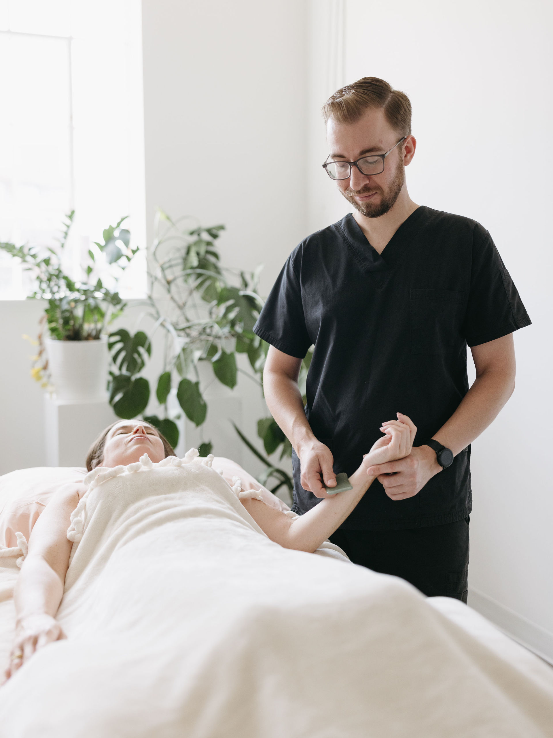 Cherry Blossom Healing Arts acupuncturist performing Gua Sha therapy on a women laying on her back